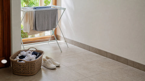 Kaos kaki bersih di area laundry rumah dengan sepatu dan rak jemur sebagai ilustrasi cara mengatasi bau setelah dicuci